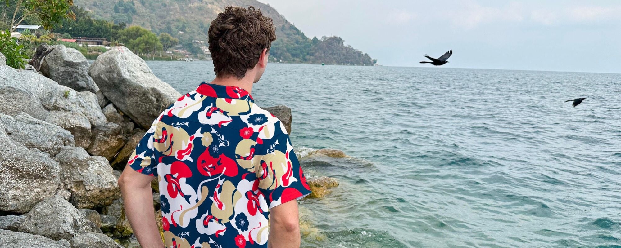 man on beach looking at water wearing an anime koi modren shirt