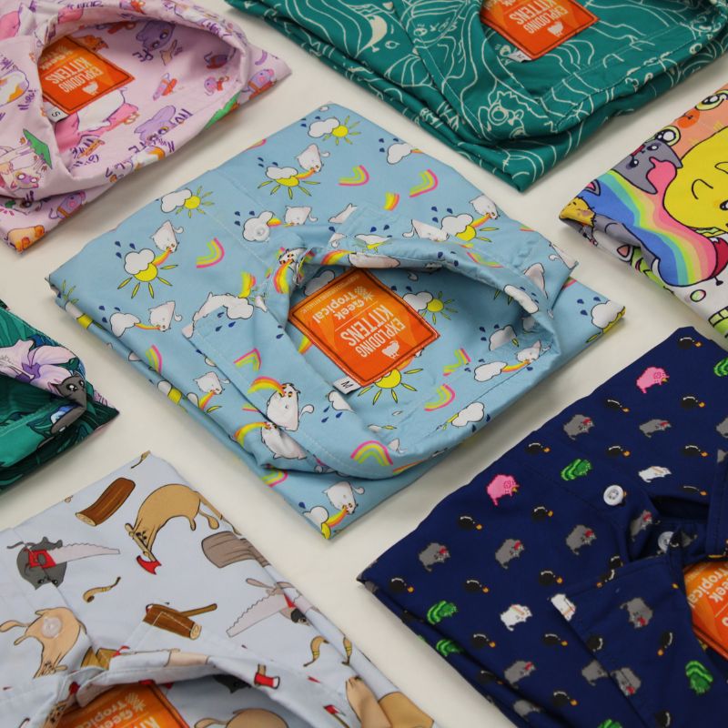Colorful Geek Tropical Shirts with Exploding Kittens Designs laying down on the floor.