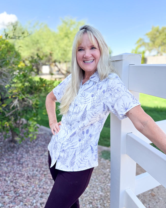 Woman in a white and purple floral patterned button up collared shirt made to fit to a woman's body